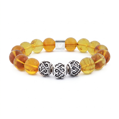 A beaded stretch bracelet featuring translucent amber-yellow glass beads with natural inclusions, accented by three ornate silver spacer beads and a silver magnetic clasp, shown on a plain white background.