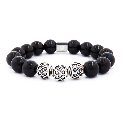 A beaded bracelet featuring glossy black round beads, three ornate silver Celtic knot style spacer beads, and a silver magnetic clasp, shown on a plain white background.
