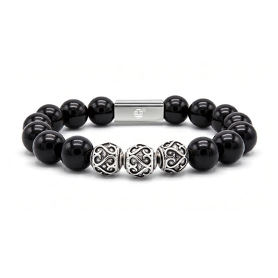 A beaded stretch bracelet featuring glossy black round beads, three ornate silver filigree spacer beads, and a polished silver magnetic clasp, shown on a clean white background.